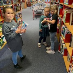 Tre børn leder efter bøger på biblioteket