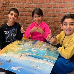 Trois enfants lisent ensemble dans un livre surdimensionné