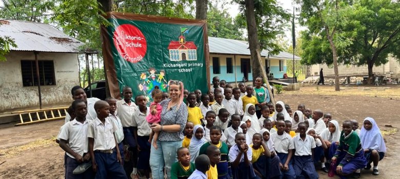 Janine Hundt et les enfants de l'école partenaire en Tanzanie devant la bannière de l'école