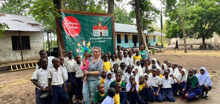 Janine Hundt et les enfants de l'école partenaire en Tanzanie devant la bannière de l'école